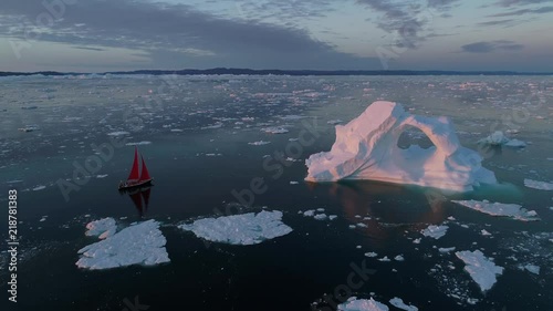 drone view Greenland iceberg at sunrise with red sail ship photo