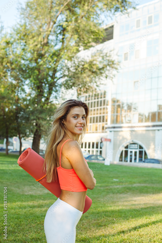 Young beautiful woman in sportswear holding a training mat Young beautiful woman in sportswear holding a training mat
