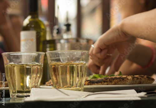 Simple meal for two people: two glasses of white wine and pizza.