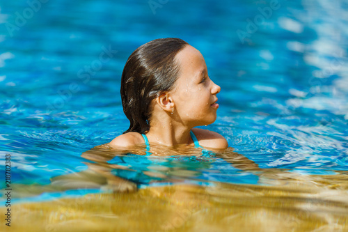 Charming 8 year old girl swims in the pool, close-up portrait 