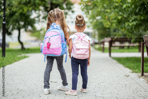 Fototapeta Naklejka Na Ścianę i Meble -  Two kids go to school with backpacks. The concept of school, study, education, friendship, childhood