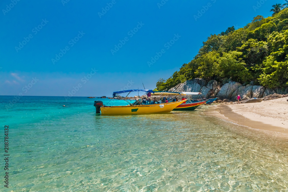Colourful tourist boats anchored on the glimmering shallow water of ...