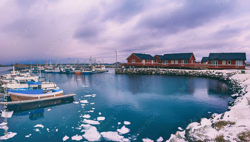 Scenic view of beautiful winter sea coast with fisherman boats and red rorbu houses at Lofoten Islands in Northern Norway