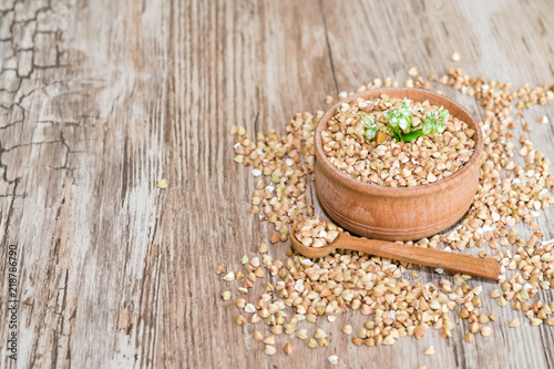 Natural organic green buckwheat in wooden plate on wooden background, selective focus, healthy eating concept 