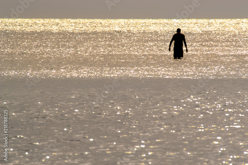 Wallpaper Mural Silhouette of a solitary man wading in shiny water at sunset on Barefoot Beach, Florida Torontodigital.ca