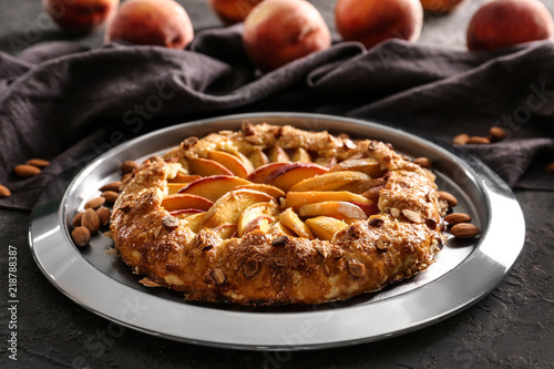 Plate with delicious peach galette on grunge table, closeup