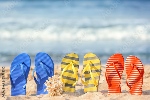 Set of beach flip-flops on sand near sea
