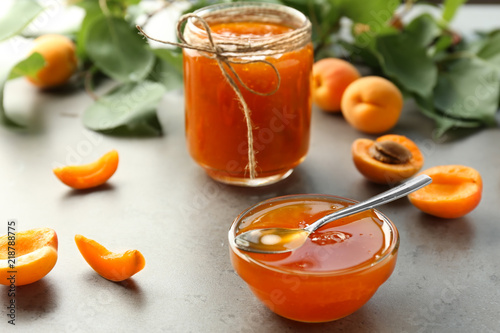 Glass bowl and jar with sweet apricot jam on table