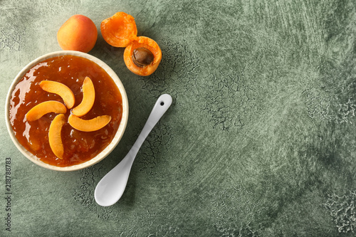 Plate with sweet apricot jam on color table