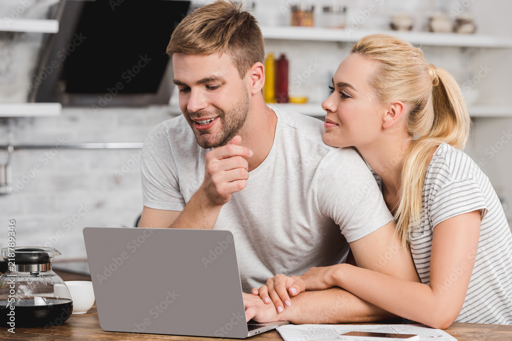 smiling girlfriend hugging boyfriend in kitchen smiling girlfriend hugging boyfriend in kitchen