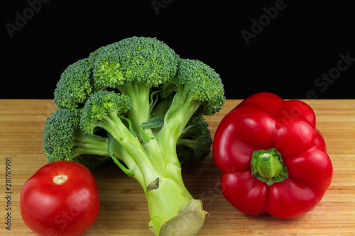 Red pepper, tomato and broccoli on wooden table