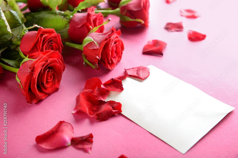 Beautiful red roses and card on color background