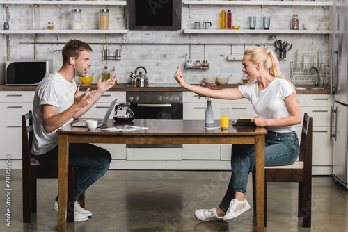 side view of young couple quarreling during breakfast in kitchen