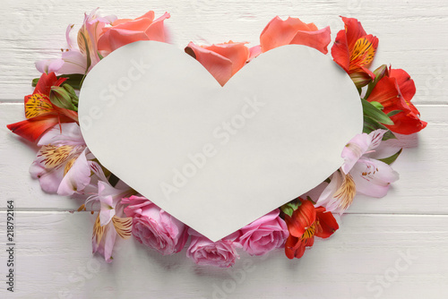 Fototapeta Naklejka Na Ścianę i Meble -  Heart shaped sheet of paper with beautiful flowers on white wooden background
