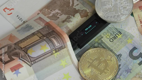 Mobile wallet for crypto. Connected to a computer to store Ethereum, Bitcoin, Litecoin and other cryptocurrencies.Euro banknotes in the background. Blur in/out, Closeup. Strobe effect on display. photo