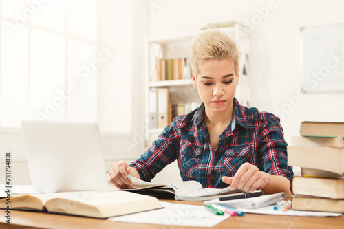 Student girl studying at table full of books