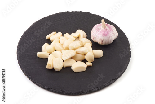 Картината върху платно Cloves of garlic on a slate plate, isolated on white background.