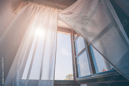 Fotografie Bright morning sun in the open window through the curtains