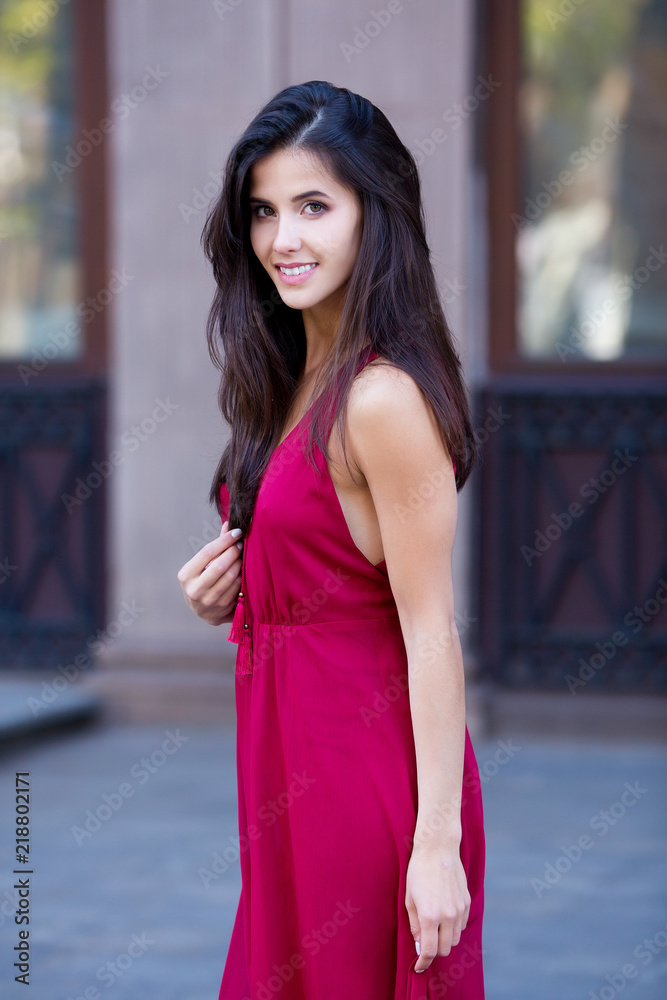 City fashion. Beautiful woman in red dress. Urban background.