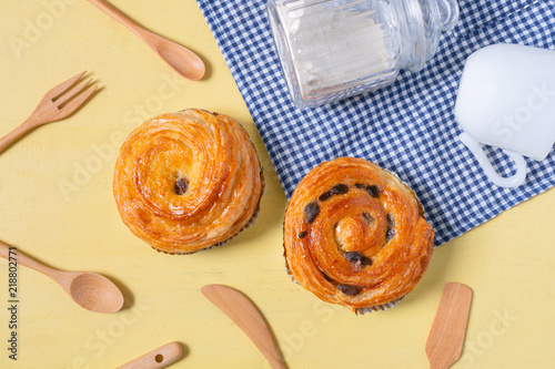 Obraz na płótnie Raisin danish pastry on the yellow wood and blue gingham check cloth. Colourful tasty sweet bakery.. w salonie