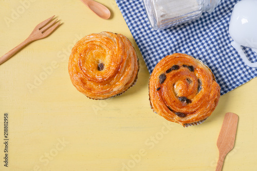 Obraz na płótnie Raisin danish pastry on the yellow wood and blue gingham check cloth. Colourful tasty sweet bakery.. w salonie