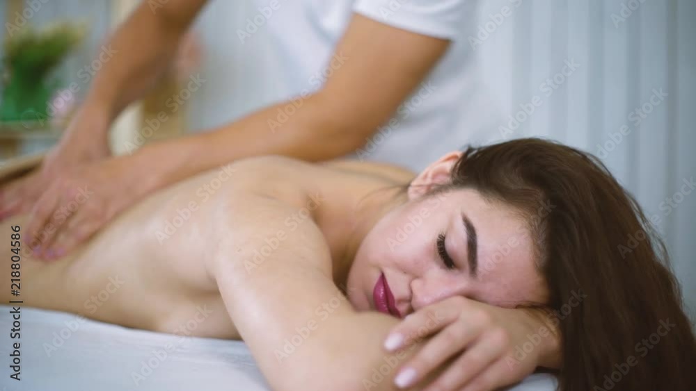 Male masseur hands massaging beautiful woman back in spa salon. Young female enjoying professional spine and back treatment. Rehabilitation, medicine, manual therapy, beauty, health and skin concept Male masseur hands massaging beautiful woman back in spa salon. Young female enjoying professional spine and back treatment. Rehabilitation, medicine, manual therapy, beauty, health and skin concept