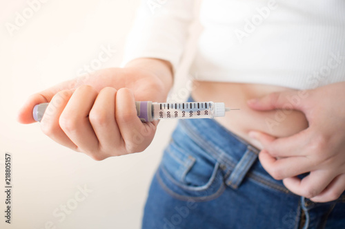 Close up of female diabetes patient making subcutaneous insulin injection into her abdomen with insulin pen syringe for at home. Diabetes, health care and medical concept. Diabetes World Day.