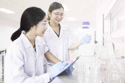 Interior of clean modern white medical or chemical laboratory background.Laboratory scientists working at lab with test tubes and report. Laboratory concept with Asian woman chemists.