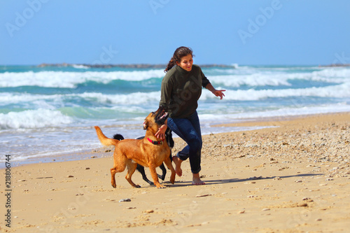 Teenage girl  playing with her dogs on the beach
