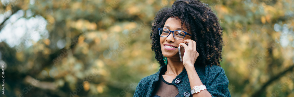 Happy black woman during a mobile phone call in autumn - obrazy, fototapety, plakaty 