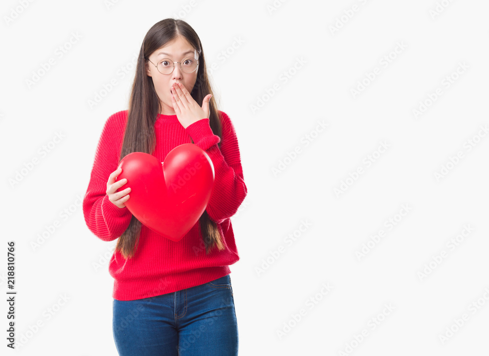 Young Chinese woman wearing graduate uniform red heart cover mouth with hand shocked with shame for mistake, expression of fear, scared in silence, secret concept Young Chinese woman wearing graduate uniform red heart cover mouth with hand shocked with shame for mistake, expression of fear, scared in silence, secret concept