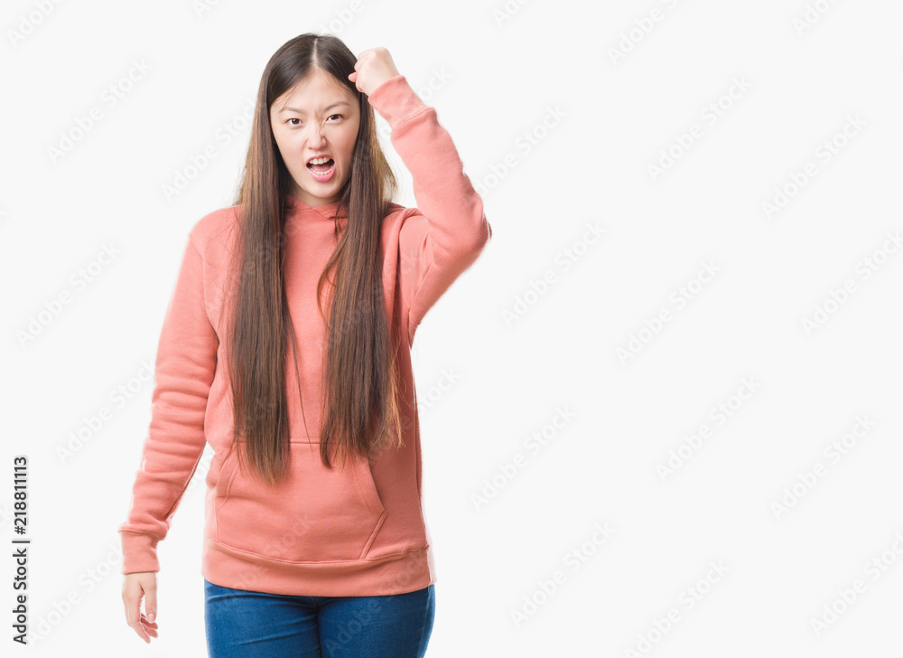 Young Chinese woman over isolated background wearing sport sweathshirt angry and mad raising fist frustrated and furious while shouting with anger. Rage and aggressive concept. Young Chinese woman over isolated background wearing sport sweathshirt angry and mad raising fist frustrated and furious while shouting with anger. Rage and aggressive concept.