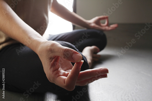 Yoga girl meditating indoor and making a zen symbol with her hand. Closeup of woman body in yoga pose