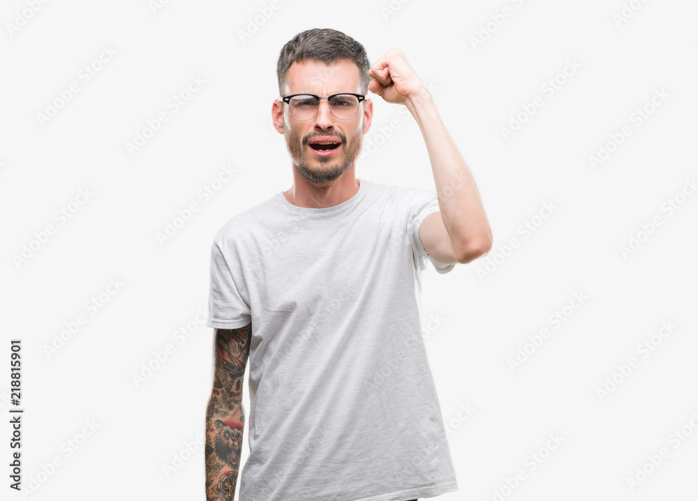 Young tattooed adult man angry and mad raising fist frustrated and furious while shouting with anger. Rage and aggressive concept. Young tattooed adult man angry and mad raising fist frustrated and furious while shouting with anger. Rage and aggressive concept.