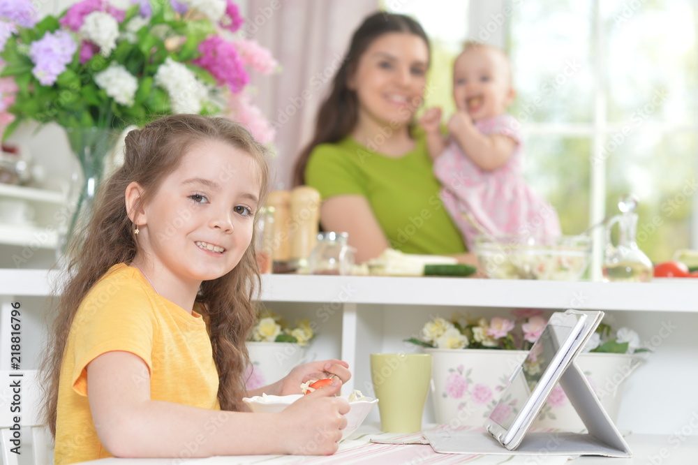 Cute little girl eating fresh salad at kitchen table Cute little girl eating fresh salad at kitchen table