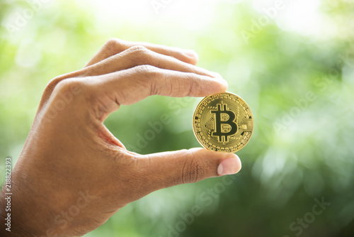 Golden Bitcoin in a man hand, Digital symbol of a new virtual currency.