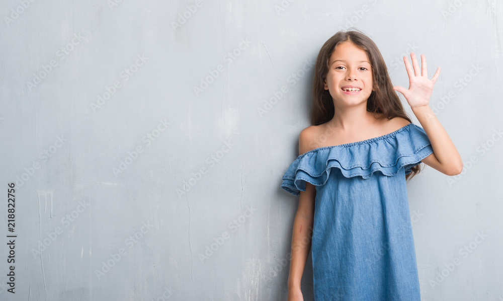 Young hispanic kid over grunge grey wall showing and pointing up with fingers number five while smiling confident and happy. Young hispanic kid over grunge grey wall showing and pointing up with fingers number five while smiling confident and happy.