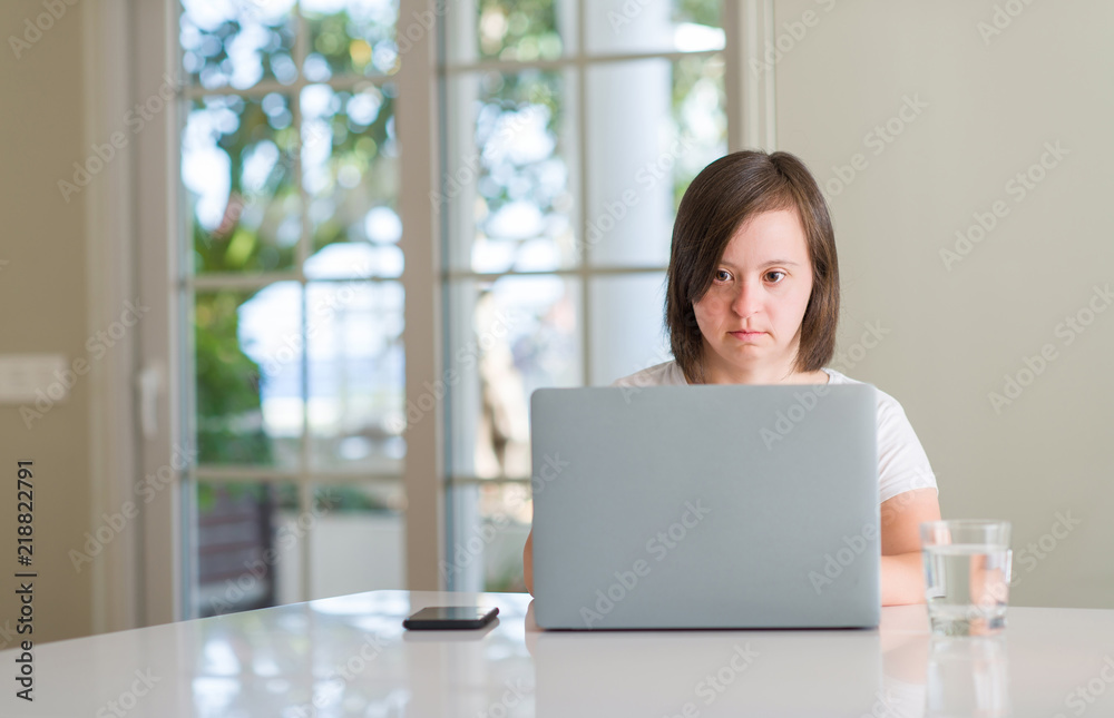 Down syndrome woman at home using computer laptop with a confident expression on smart face thinking serious Down syndrome woman at home using computer laptop with a confident expression on smart face thinking serious