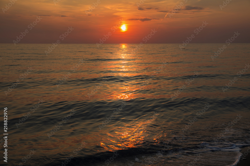 Sunset at the beach with a red sky and reflection on the waves