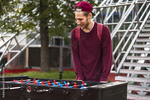 one young man in casual clothes playing foosball in the public park. table games concept