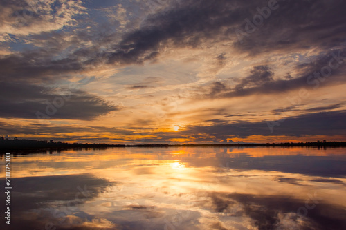 Sunset in the lake. beautiful sunset behind the clouds above the over lake landscape background. dramatic sky with cloud at sunset