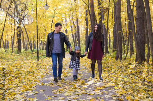 people, family and leisure concept - family with a young daughter walking in autumn park