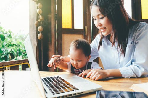 Business woman teaching her child about investment with multimedia and book, home school education.