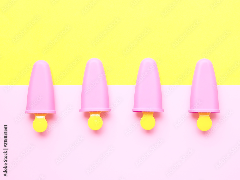 Flat lay colorful summer theme, Top view of pastel pink and yellow plastic ice pop maker on background, joy and freshness concept