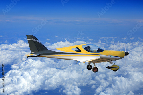 Piękny żółty samolot, awionetka nad chmurami.