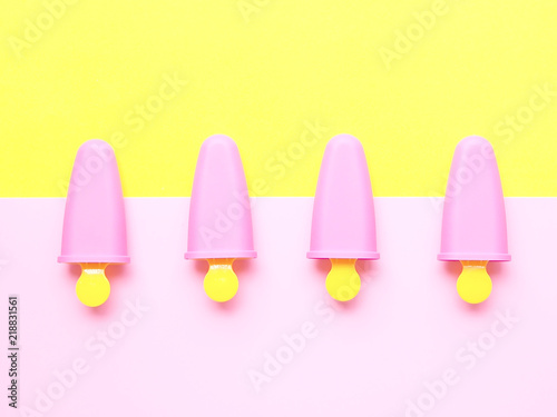 Flat lay colorful summer theme  Top view of pastel pink and yellow plastic ice pop maker on background  joy and freshness concept
