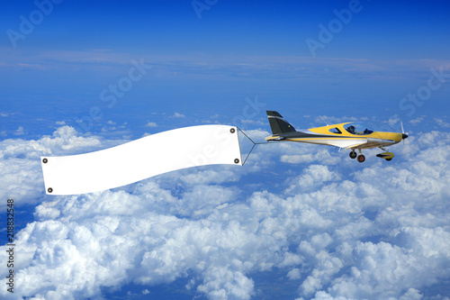 Samolot, awionetka z bilbordem reklamowym nad chmurami.