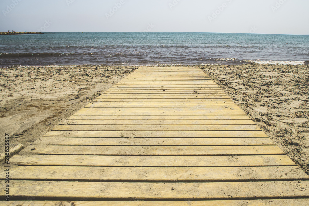 footbridge of wooden boards with direction to the sea