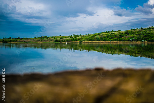 A simple landscape in the Rostov region in Russia, the river - Seversky Donets, Don. Spring is the beginning of summer. Green vegetation, trees. Cool fresh lake water. Colorful sky and its reflection 