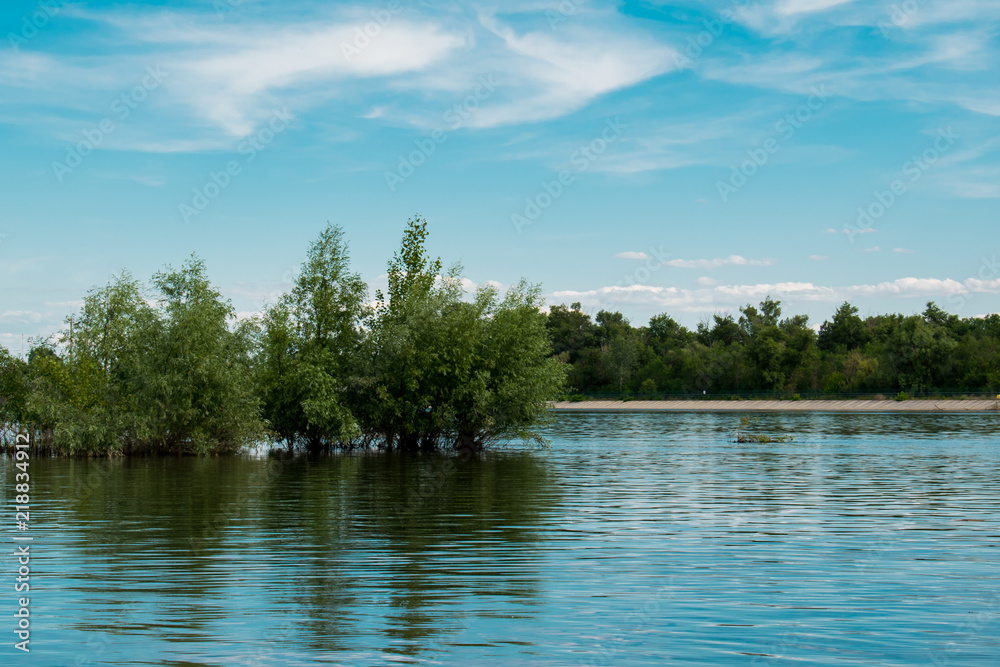 Obraz premium A simple landscape in the Rostov region in Russia, the river - Seversky Donets, Don. Spring is the beginning of summer. Green vegetation, trees. Cool fresh lake water. Colorful sky and its reflection